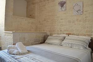 阿尔贝罗贝洛Dimore Vino&Amore的砖墙房间的一个床位