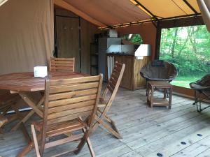 贝莱姆Camping Du Perche Bellemois的帐篷内的木桌和椅子