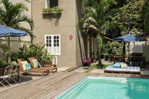 里约热内卢伊帕奈玛海滩别墅酒店的一座带椅子和遮阳伞的游泳池位于一座建筑旁边