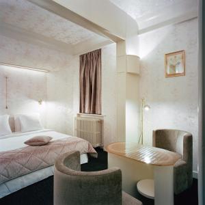 布鲁塞尔Le Berger Hotel的酒店客房带一张床、一张桌子和椅子