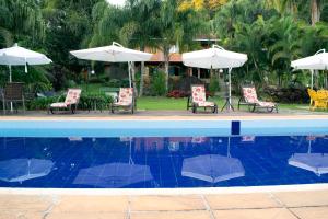 尤西德福拉Pousada Lago das Pedras的一个带椅子和遮阳伞的游泳池