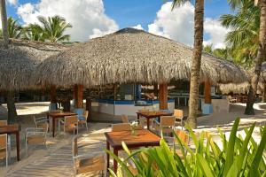 蓬塔卡纳蓬塔卡纳伊贝罗斯塔度假酒店的一间带桌椅和稻草伞的餐厅
