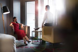 南京南京禄口机场铂尔曼大酒店的坐在酒店房间椅子上的男人和女人