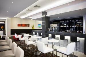 墨尔本Mantra Melbourne Airport的一间设有白色椅子的餐厅和一间酒吧