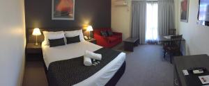 利物浦Hunts Hotel Liverpool的酒店客房设有一张大床和一张红色沙发。