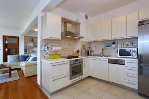扎达尔普塔米卡公寓的厨房配有白色橱柜和不锈钢冰箱