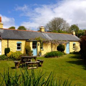 JohnstonCharming Welsh Cottage的黄色小屋前面设有野餐桌