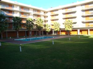 坎布里尔斯Apartamento Playa Esquirol的一座带游泳池和棕榈树的大型建筑