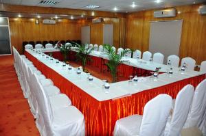 达卡Quality Inn Dhaka的一张长桌子,房间配有白色椅子