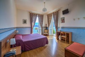 格里安泰卡德纳比亚里维埃拉酒店的一间卧室配有紫色的床、书桌和窗户。
