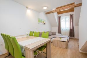 克拉尼斯卡戈拉Podkoren Apartments的一间带桌子和绿色椅子的用餐室
