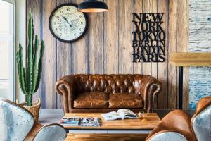耶尔Ibis Styles Hyères Rooftop & Spa的客厅配有棕色皮沙发和时钟