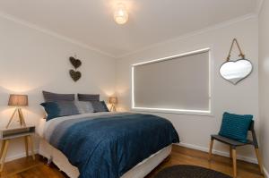 彭古因企鹅海滩度假屋的一间卧室设有一张床、一个窗口和一把椅子