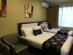 墨尔本帕克斯奎尔汽车旅馆和服务式公寓的酒店客房,配有两张床和椅子