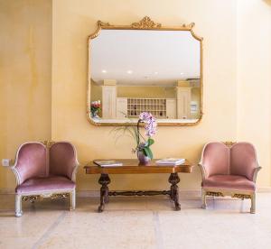 萨罗Hotel Spiaggia d'Oro - Charme & Boutique - Garda Lake Collection的两把椅子和一张桌子,墙上挂着镜子