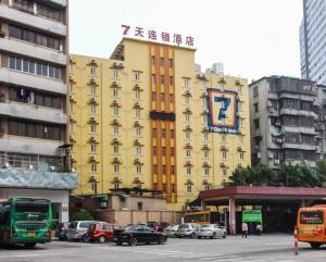 广州7天连锁酒店广州黄花岗地铁站店的一座黄色的建筑,前面有汽车停放