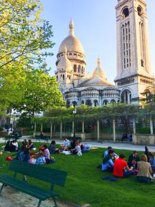 巴黎MONTMARTRE ROMANTIC - chambres d'hôtes de charme à Montmartre - Paris的一群人坐在一座建筑前面的草上