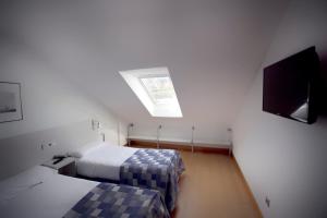 宏达瑞比亚Apartamentos Jauregui的一间卧室设有两张床和天窗