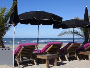 拉格朗德默特Vittoria Immobilier 12 - Vue Dégagée - Terrasse - chèques vacances acceptés的海滩上的一组椅子和一把遮阳伞