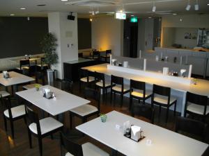 丰桥市冈田屋碧沙酒店的一间设有白色桌椅的餐厅和一间酒吧