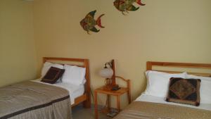 佩达西镇Hostal Doña Maria的一间卧室配有两张床和一张带台灯的桌子