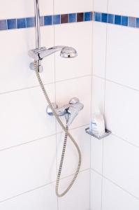艾谢德维斯特瓦尔德酒店的浴室铺有白色瓷砖,配有淋浴头。