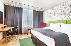 赫尔辛基赫尔辛基市中心假日酒店的酒店客房设有一张大床、一张书桌和一张书桌。