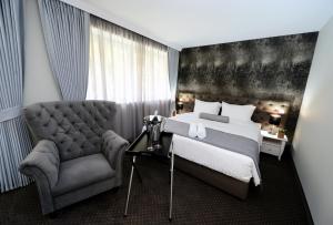 斯科普里亚力山大广场精品酒店的一间卧室配有一张床和一把椅子
