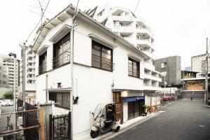 东京Araiya Tokyo -Private Townhouse-的街上有一辆白色的房屋,上面有一辆摩托车