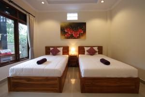 乌布KT夸雅斯民宿酒店的墙上画画的房间里设有两张床