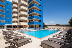 普拉亚登博萨Ibiza Heaven Apartments的一座大楼前的游泳池,配有躺椅