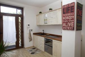 坎帕尼亚诺·迪罗马Just House的厨房配有白色橱柜和墙上的标志