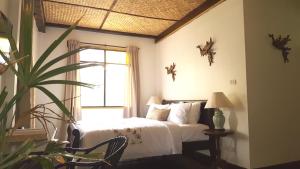 曼谷曼考拉别墅旅馆的一间卧室,配有床、窗户和植物