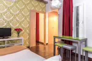 巴塞罗那老城区公寓的一间卧室配有一张床、一张书桌和红色窗帘