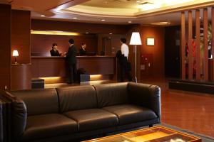 弘前市弘前广场酒店 的带沙发的大堂,有人站在酒吧