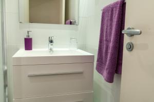 巴塞罗那康德古尔公寓式酒店的一间带水槽和紫色毛巾的浴室