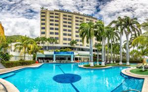 Macuto奥莱加勒比酒店的拥有大型游泳池和棕榈树的酒店