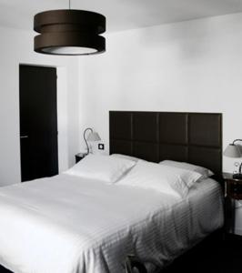 苏斯通L auberge de la pointe的一间卧室配有一张白色大床和黑色床头板