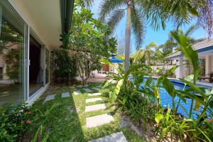 纳通市BAAN RIM TALAY - Beach Side 2 Bed Pool Villa的一座花园,花园旁设有游泳池