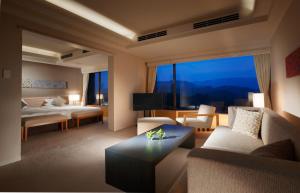 鸟羽图巴国际酒店的带沙发和床的客厅以及大窗户。