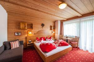 贝旺阿尔彭布里克旅馆的一间卧室配有一张带红色枕头的床