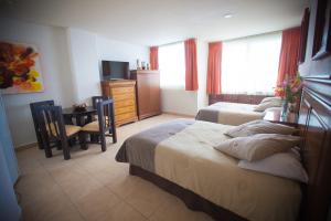 布塞里亚斯Banderas Suites的一间卧室配有两张床、一张桌子和一张书桌