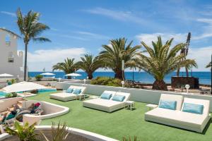 科斯塔特吉塞海王星套房酒店 - 仅限成人的一个带白色椅子和棕榈树的庭院以及大海