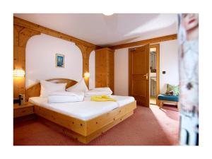 伊姆斯特林瑟霍夫阿尔彭旅馆的一间卧室配有一张带白色床单的木床
