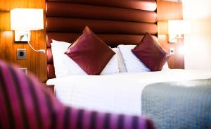 塔姆沃思德雷顿庄园酒店的酒店的客房 - 带红色和白色枕头的床