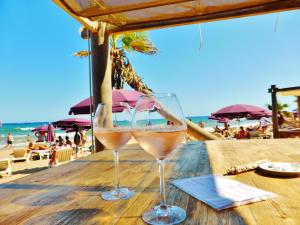 弗雷瑞斯Carazur Mobilhomes Camping Fréjus的两杯酒坐在海滩附近的桌子上