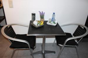 马尔梅迪Chez Martine的一张餐桌,配有两把椅子和一张黑桌,两面 ⁇ 