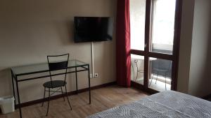 艾克斯莱班车站酒店的一间卧室配有一张桌子、一台电视和一张床