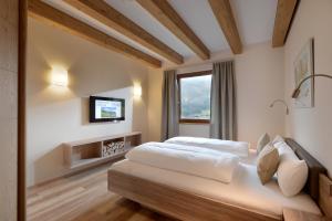 布利克森塔勒Resort Tirol Brixen am Sonnenplateau的一间卧室设有两张床,墙上配有电视。