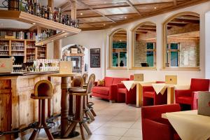 蒂罗尔-基希贝格科诺纳克酒店的一间设有红色椅子的餐厅和一间酒吧